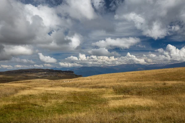 Herfst blauwe hemel met witte wolken en de bergen op de vergeelde — Stockfoto