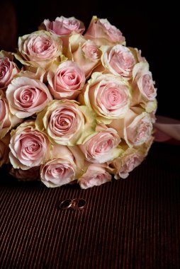 Koyu arkaplanda yüzükler olan düğün buketi.