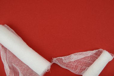 Kırmızı arka planda açılmamış iki bandaj var.