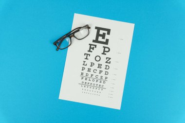 Mavi arka planda gözlük ve görüş testi masası