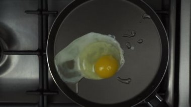 Bir erkek eli yumurtayı kızgın tavaya kırar. Kızartmaya başla.
