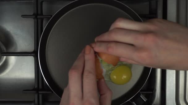 A woman hand breaks an egg into a hot frying pan. Start frying. — Stock Video