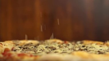 Pizza döner ve üzerine peynir dökülür. Yavaş Hareket Videosu