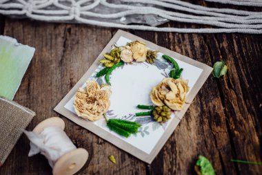 Tahta bir masanın üzerinde boho tarzı bir davetiye var.