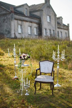 Düğün dekoru. Bir sandalye, yanında bir vazo çiçek, etrafında şamdanlar.