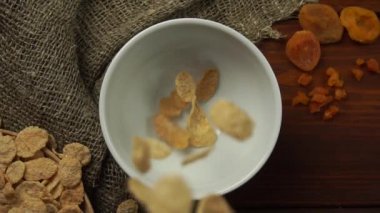 Mısır gevrekleri beyaz bir tabağa dökülür. Üst Manzara. Yavaş çekim