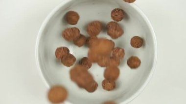 Kahvaltı gevreği. Çikolata topları yavaşça kaseye düşer. Üst görünüm. 