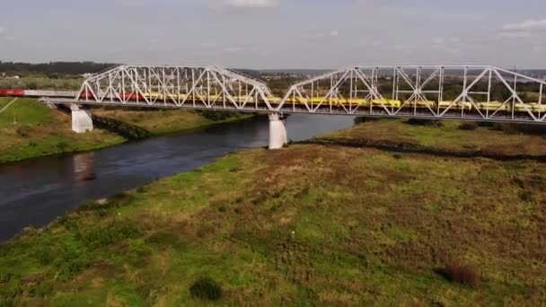 Pociąg towarowy jeździ po moście kolejowym nad rzeką.Wideo lotnicze — Wideo stockowe