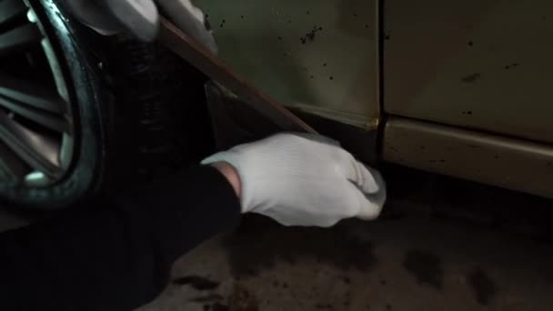 Ein Mann säubert ein Auto mit einer Feile von Rost — Stockvideo