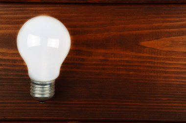 Soldaki ahşap arka planda bir ampul. Üst görünüm