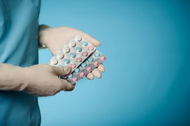 Tıbbi eldiven giymiş bir kadın bir paket hap taşır..