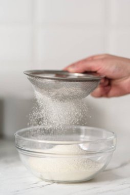 Bir kadının elleri, süzgeçten un geçirirken yakın plan çekimleri..
