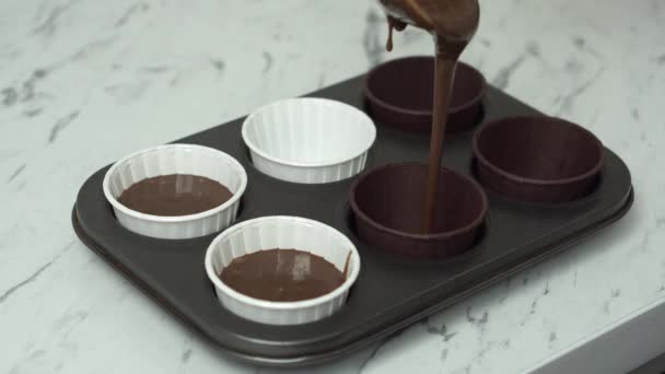 The chocolate muffin dough is poured into a mold with beautiful paper cups. — Stock Video