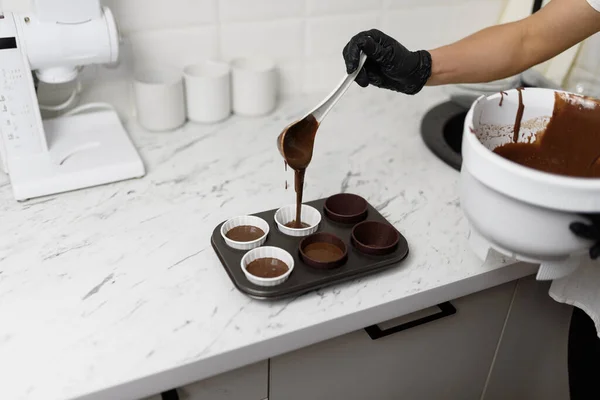 Chocolate cake batter is poured into a mold with beautiful paper cups.