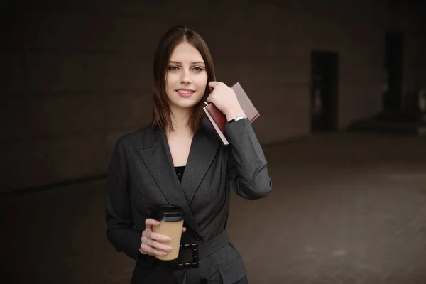 Młoda bizneswoman z notatnikiem i kawą na ulicy — Zdjęcie stockowe
