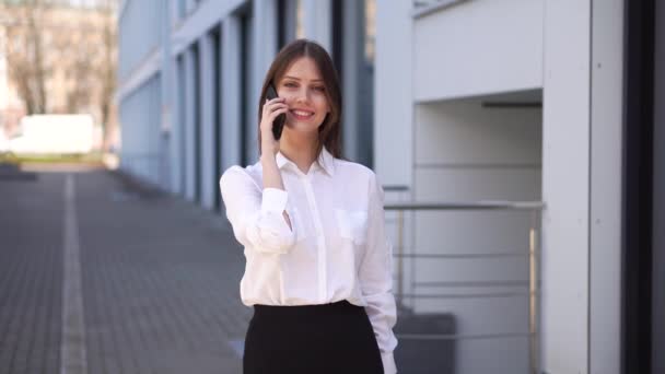 Una joven sostiene su teléfono inteligente al oído y escucha un mensaje de audio. — Vídeos de Stock