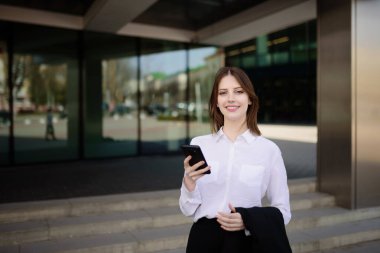 Genç, güzel, gülümseyen kız cep telefonundaki bir mesaja cevap veriyor.