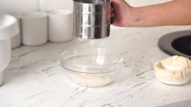 Un süzgecinden un geçen bir kadının ellerine yakından bakın..