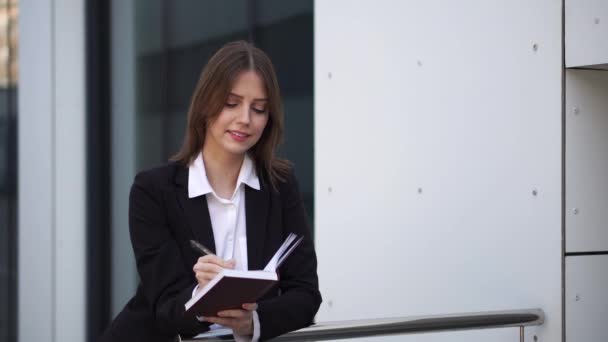 Eine selbstbewusste Geschäftsfrau notiert in einem Notizbuch — Stockvideo