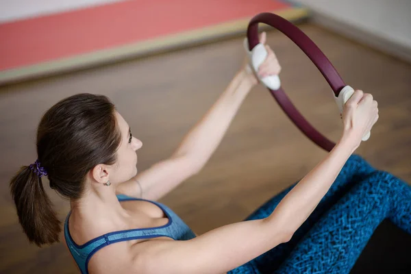 V tělocvičně, mladá žena ve sportovním oblečení svírá kroužek s pilates — Stock fotografie