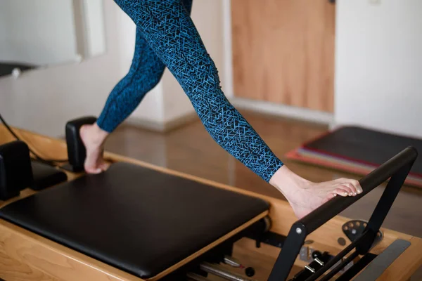 Eine athletische Frau macht eine Übung auf einem Reformer in der Turnhalle. Füße aus nächster Nähe. — Stockfoto