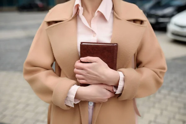 Una mujer sostiene un cuaderno en sus manos y se lo presiona, de cerca — Foto de Stock