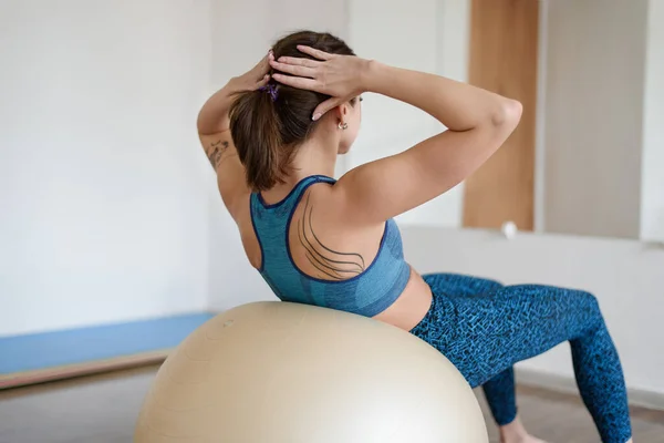 Fit žena trénuje tlačit na fitness míč ve sportovní tělocvičně. Pohled zezadu — Stock fotografie