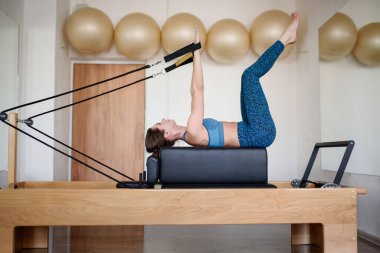 Spor giyimli bir kadın spor salonunda pilates yapıyor. Kenar manzaralı.