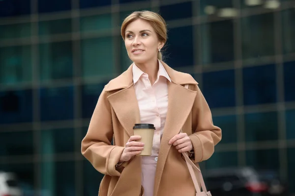 Una hermosa mujer camina por el centro de la ciudad con una taza de café — Foto de Stock