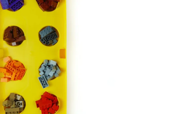 Un sacco di blocchi di giocattoli di diversi colori sono nelle celle nella scatola gialla. — Foto Stock