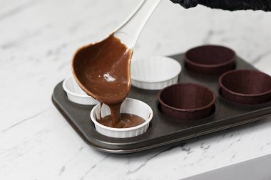 Çikolatalı kek hamuru güzel kağıt bardaklarla kalıba dökülüyor..