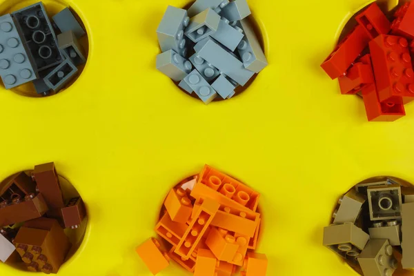 Un sacco di blocchi di giocattoli di diversi colori sono nelle celle nella scatola gialla. — Foto Stock