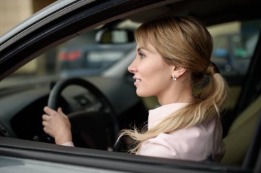 Yeni bir araba kullanan mutlu ve güzel bir kadın sürücü. Kasabaya yeni bir sürücü geldi.