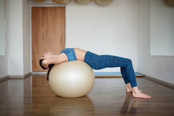 Mladá atletka trénuje svaly na fitness plese v tělocvičně. Boční pohled — Stock fotografie