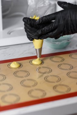 Bir kadın hamur işini bir hamur torbasının içinden fırın tepsisine sıkıştırır.