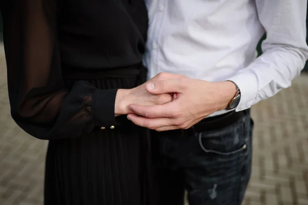 Un jeune couple amoureux se tient debout dans la rue et se tient la main, sans visage. — Photo
