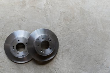 Gri beton zeminde iki yeni fren diski var. Üst manzara.