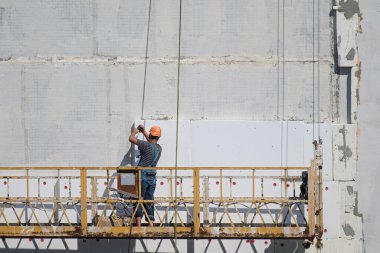 İnşaatçı evi dışarıdan izole ediyor. İnşaat asansörü..