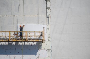 İnşaatçı evi dışarıdan izole ediyor. İnşaat asansörü. Kopyalama alanı.