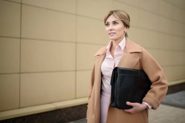 Bir kadın iş görüşmesi için elinde belgelerle sokakta yürüyor.