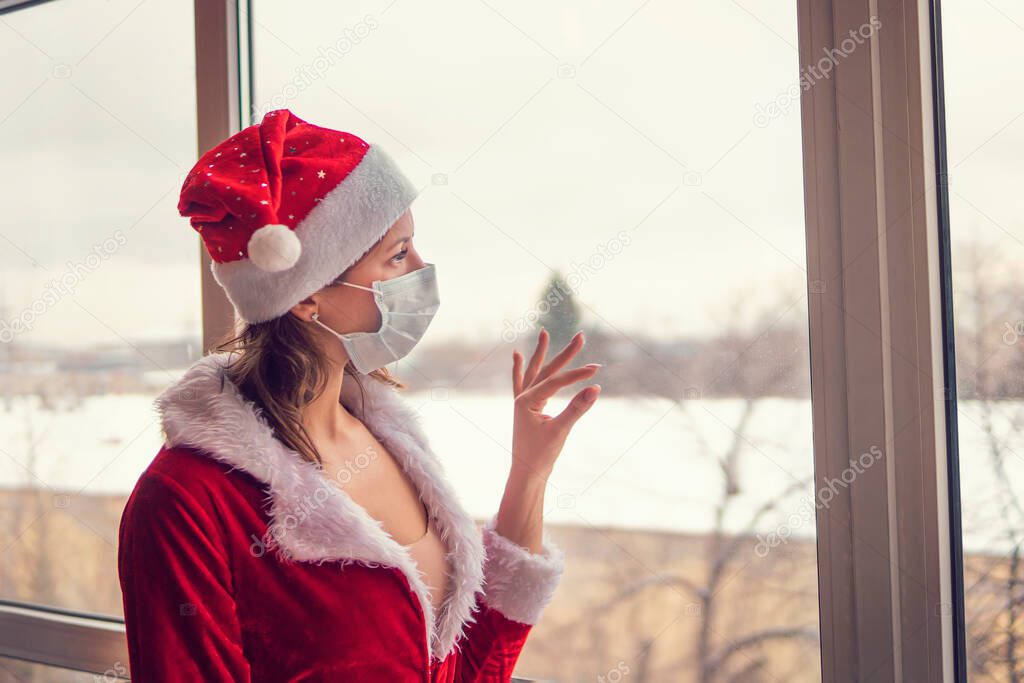 Girl in mask looks out window, in quarantine with reflection. quarantine. Powerful outbreak of coronavirus. a young pretty girl with sad emotion. self-isolation, ari, ard, acute respiratory disease