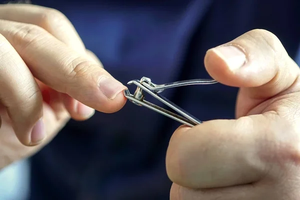 hand manicure with nail clipper. close up over black background. self-cutting nails.