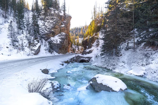 Il flusso di un bellissimo fiume blu vicino alla strada di montagna in una pineta. Paesaggio invernale. — Foto Stock