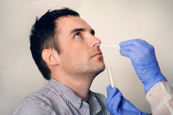 Лікар, який приймає пробний зразок носового слизу з чоловічого носа, що виконує процедуру тестування на вірус дихання. Перевірка носової порожнини в ЛОР. Реакція полімеразного ланцюга PCR — стокове фото