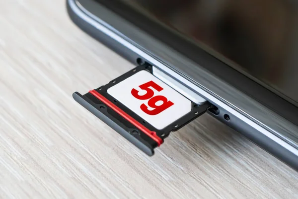 Broadband 5G mobile communication technology concept SIM card tray, dual SIM card slot with two nano SIM cards on wooden background. — Stock Photo, Image