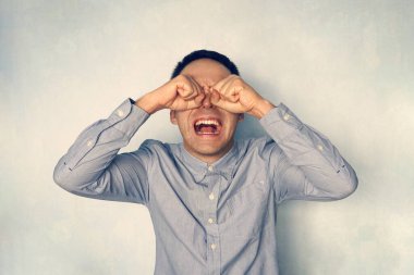 Mavi gömlekli yetişkin bir adam bağırıyor ve ağlıyor. Olumsuz duygu. İnsanlar sorunlara olumsuz tepki verir. Deli adam ağlıyor.