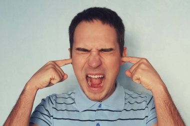 Stresli genç adamın parmaklarıyla kulaklarını tıkaması ve baş ağrısı çekerken gözlerini kapalı tutması komşulardan gelen korkunç seslere dayanamıyor. Adam kulaklarını kapattı.