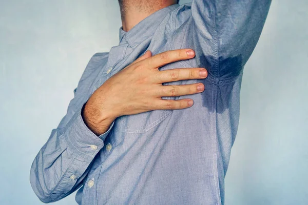 Hombre con hiperhidrosis sudando muy mal bajo la axila con camisa azul. mancha mojada en mi camisa —  Fotos de Stock
