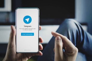 Elinde telgraf logosuyla ekranda parmağı olan akıllı telefon tutan adam.