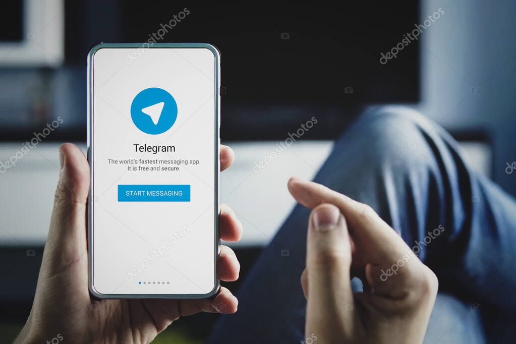 Man holding smartphone with Telegram logo with the finger on the screen at home. July 22, 2018. Barnaul, Russia.